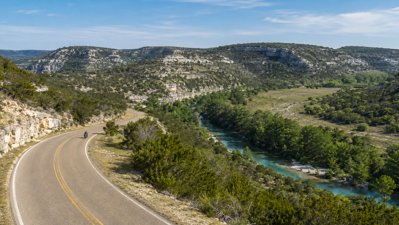 Motorcyclist riding through the limestone hills and river valleys of the Three Sisters route in Texas